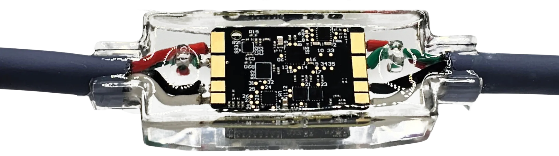 A sensor node from above, the black board with gold pads sealed in clear epoxy between two cable ends